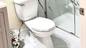 A bathroom with a toilet, a shower enclosure, and a toilet paper holder. - Modern & Cozy Stay | Self Check-In | Free Parking (Surrey)