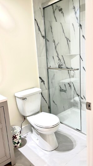 A bathroom with a toilet, a shower enclosure, and a toilet paper holder. - Modern & Cozy Stay | Self Check-In | Free Parking (Surrey)