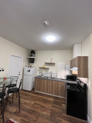 A compact kitchen with a refrigerator, microwave, stove, and a coffee maker. - Modern & Cozy Stay | Self Check-In | Free Parking (Surrey)
