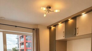 Ein Schlafzimmer mit einem großen Bett, einem Deckenventilator und Blick auf ein Gebäude durch eine Schiebetür.