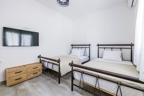 A bedroom with two beds, a wooden dresser, and a flat-screen TV mounted on the wall. - Villa Theofilos-Country pool villa-3 bedrooms-wifi-sunset & sea view (Loutraki)