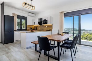 A modern kitchen with a central island, black chairs, and a dining table. - Villa Theofilos-Country pool villa-3 bedrooms-wifi-sunset & sea view (Loutraki)