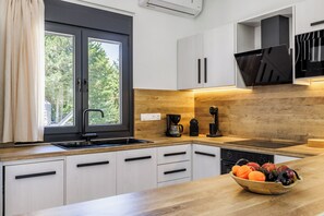 Une cuisine moderne dotée d’un plan de travail en bois, d’un lave-vaisselle encastré et d’un panier à fruits.