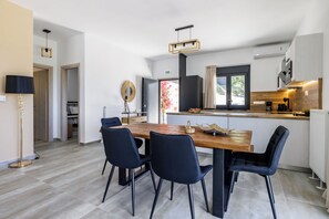 A modern kitchen with a wooden island, black chairs, and a dining table. - Villa Theofilos-Country pool villa-3 bedrooms-wifi-sunset & sea view (Loutraki)