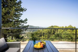 A balcony with a table set with fruit and a wicker chair, overlooking a mountainous landscape. - Villa Theofilos-Country pool villa-3 bedrooms-wifi-sunset & sea view (Loutraki)