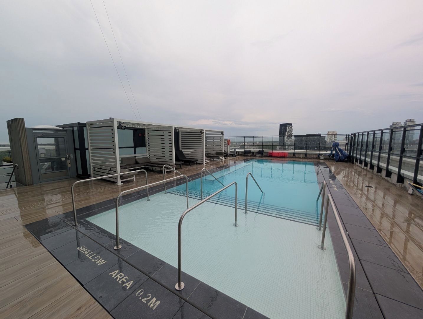 A pool area with a shallow water zone marked 'SHALLOW AREA 0.2M' and a deck with lounge chairs and a glass-enclosed structure.