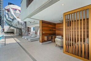 Eine moderne Hotelhalle mit einer großen Skulptur für die Hand, einem Pool und einem hölzernen Empfangsbereich.