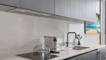 A modern kitchen with a built-in stove, a coffee maker, and a sink.