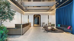 Eine moderne Lobby mit einer Rezeption, einer Sitzecke und einem großen, blauen Vorhang.