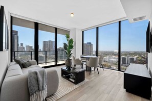 A modern living room with a sofa, coffee table, and dining area, large windows with a city view. - E11EVEN Residences Luxury Double Suite in Downtown Miami (Miami)
