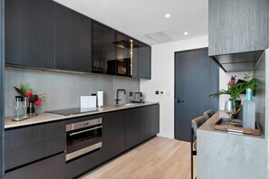 Eine moderne Küche mit dunklen Schränken, einem eingebauten Backofen und einer Arbeitsplatte mit Kaffeemaschine.