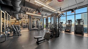 Et moderne fitnesscenter med forskellig træningsudstyr, store vinduer og udsigt over byen.