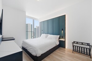 Um quarto moderno com uma cama, mesa de cabeceira e vista para a paisagem urbana.