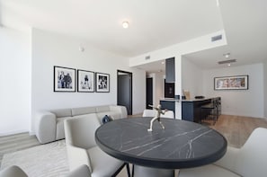 Uma sala de estar moderna com uma mesa redonda de mármore, um sofá cinzento e um bar com banquetas.