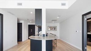 A modern kitchen with a central island, wooden flooring, and recessed lighting. - Luxury Condo w/ Rooftop Pool & City Views (Miami)