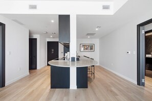 Cozinha moderna com ilha central, piso de madeira e iluminação embutida.