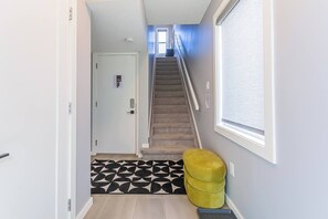 A hallway with a carpeted staircase, a door, and a window. - Luxury Boutique Stay w/ Hot Tub | Sleeps 8 | Near Golf Courses (Edmonton)