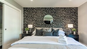 Ein Hotelzimmer mit einem großen Bett, einem Kopfteil im Steinoptik, zwei Nachttischen inklusive Lampen und einem Spiegel.