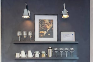 A wall with a framed artwork, a business license certificate, and a shelf with glasses and jars. - Luxury Boutique Stay w/ Hot Tub | Sleeps 8 | Near Golf Courses (Edmonton)