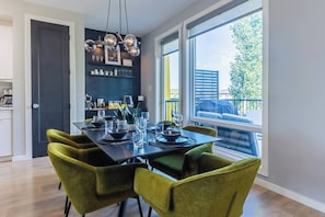 A dining area with a table set for four, chairs, and a modern chandelier. - Luxury Boutique Stay w/ Hot Tub | Sleeps 8 | Near Golf Courses (Edmonton)