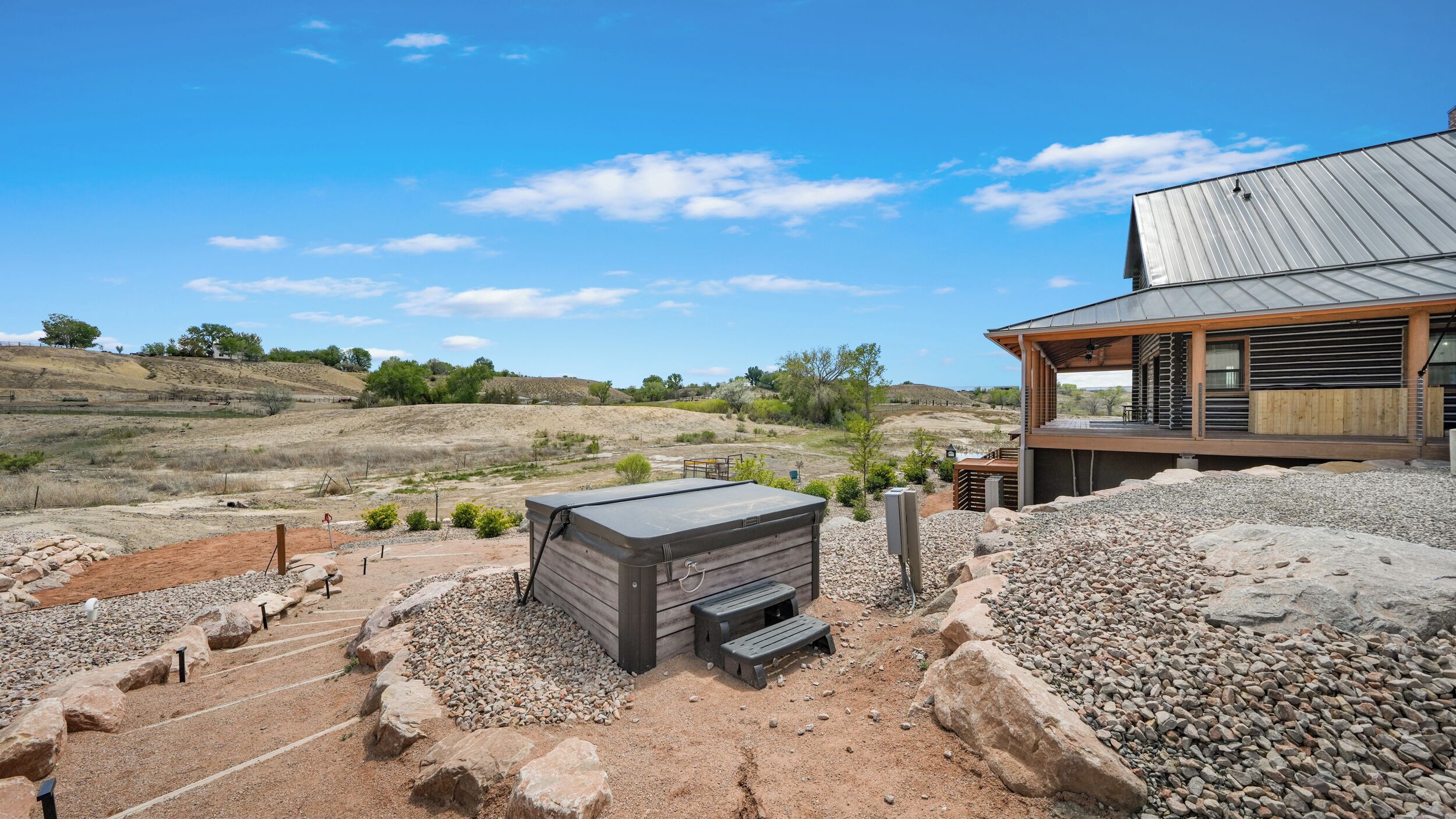 A modern house with a patio area, a wooden deck, and a view of the surrounding landscape.