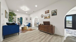 Un salón amplio con un sofá azul, un mueble de madera y una alfombra de cuero de vaca.
