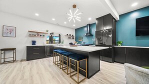 Una cocina moderna con una isla central, taburetes de bar y un ventanal grande.