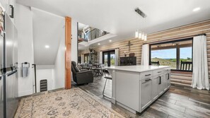 Une cuisine moderne dotée d’un îlot central, d’un coin repas et offrant une vue sur l’extérieur.