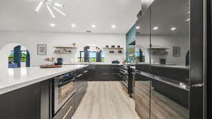 Una cocina moderna con una isla central, electrodomésticos integrados y vistas al exterior.