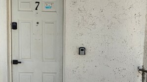 Una puerta blanca con el número 7, un timbre y una ranura para correo en una pared con textura.