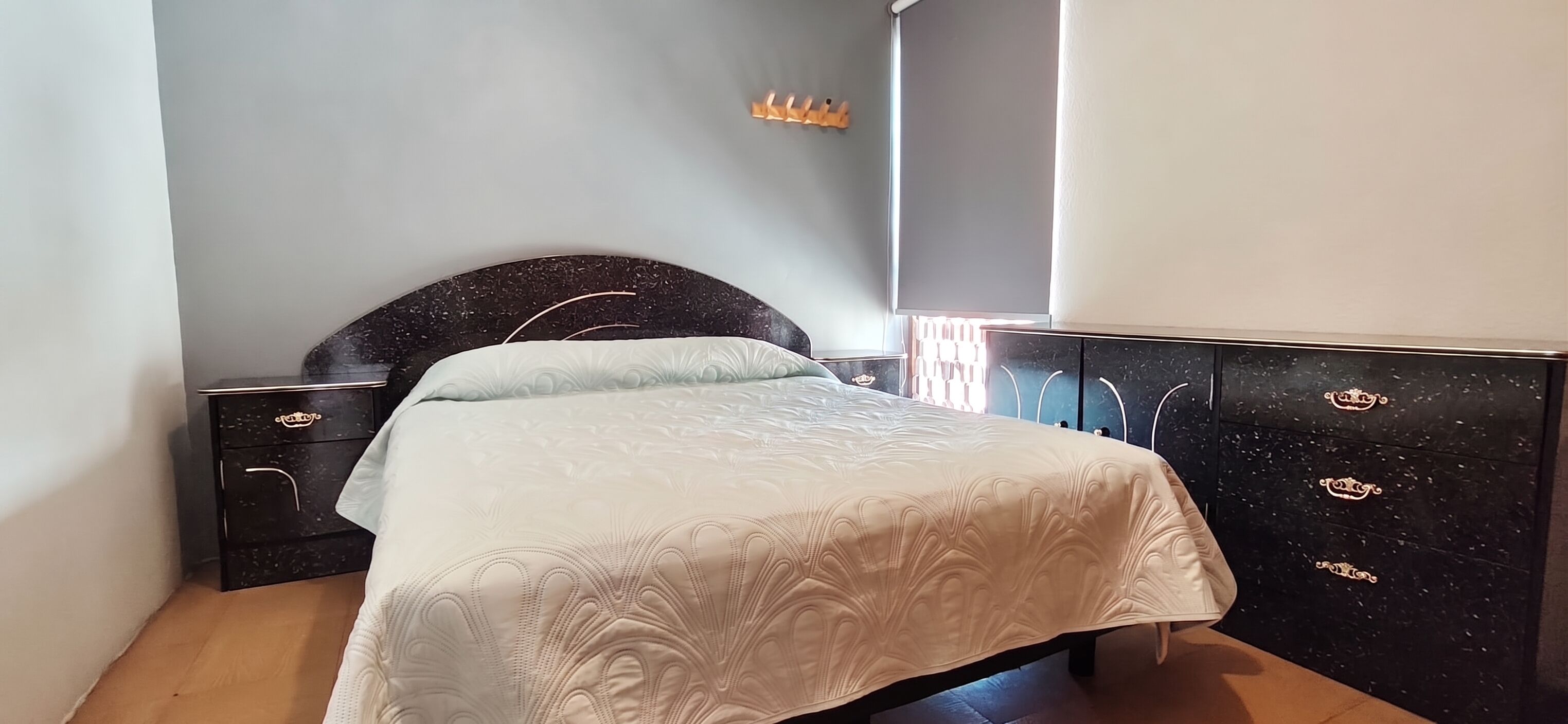 Une chambre à coucher avec un lit, une commode et une table de chevet.