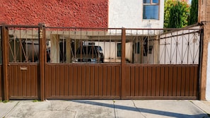 A gated entrance with a metal gate and a vehicle parked inside.