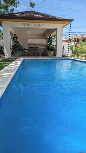 A swimming pool with a covered area labeled 'DON ELISEO' and a clear blue sky.