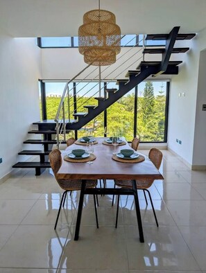A modern dining area with a long table, chairs, and a staircase with a black railing. - Penthouse with 360 views (Santiago de los Caballeros)