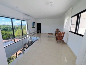 A spacious room with a balcony, a dining area with chairs, and a view of greenery outside. - Penthouse with 360 views (Santiago de los Caballeros)