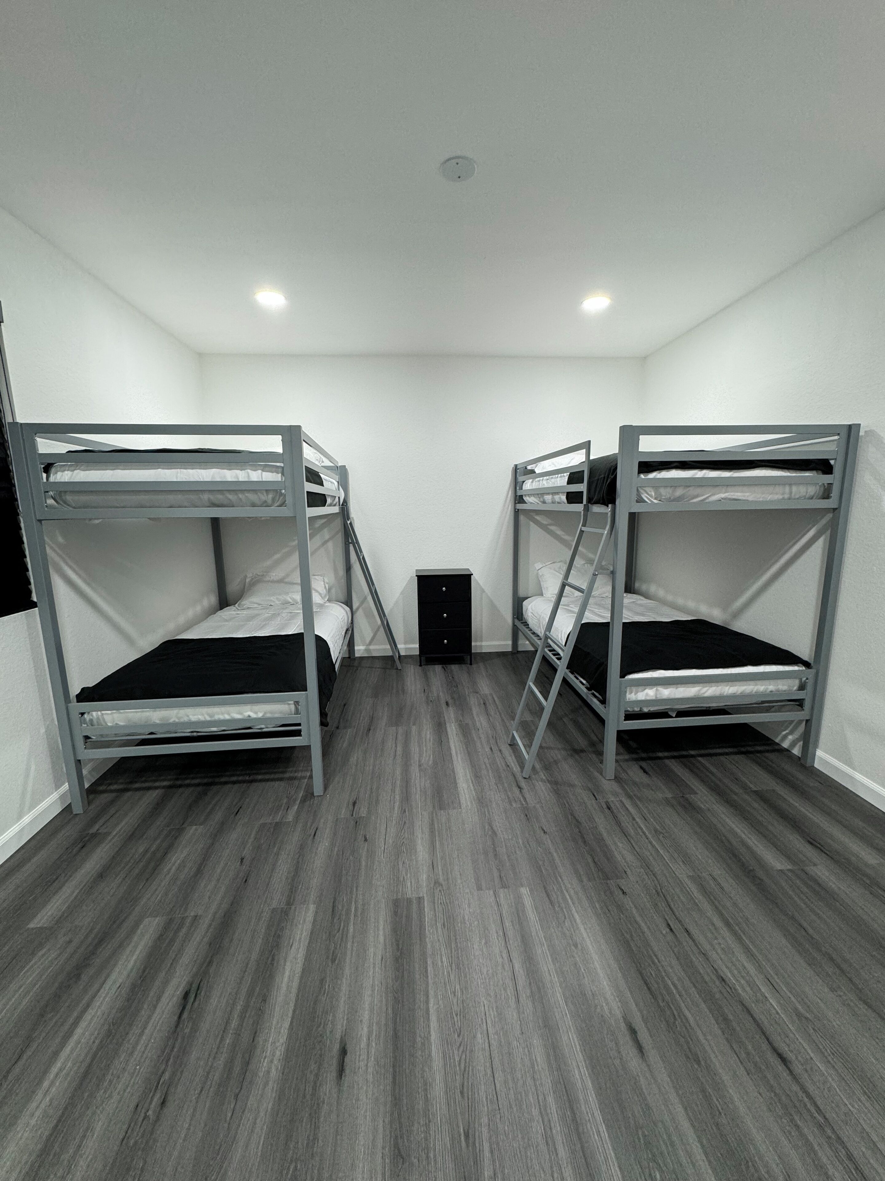 A room with two bunk beds, a small dresser, and a ladder.