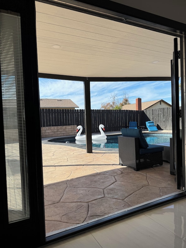 A backyard with a swimming pool, two swan floats, and outdoor furniture. - Modern Spacious 4-bedroom house with AC in quaint Spring Valley (Spring Valley)