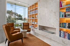 Un espacio lounge moderno con sillones de cuero, chimenea de mármol y estanterías llenas de libros.