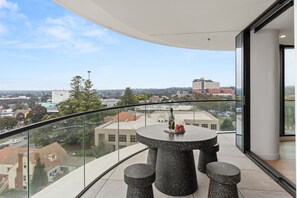A balcony with a round table, two chairs, and a bottle of wine. - Altura Bay Luxury Residence Frankston (Frankston)