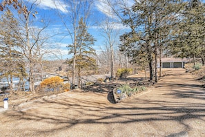 A paved pathway leading to a building with a garage, surrounded by trees and a clear sky. - Amazing Location~Game Room~Swim Dock~Boat Rental! (Osage Beach)