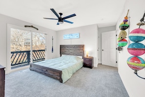 A bedroom with a bed, a nightstand, a ceiling fan, a window with a view, and a wall with colorful balls. - Amazing Location~Game Room~Swim Dock~Boat Rental! (Osage Beach)