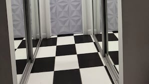 A hallway with a checkered floor, a geometric patterned door, and mirrored walls. - Spacious Studio Apartment Best Location (Miami Beach)