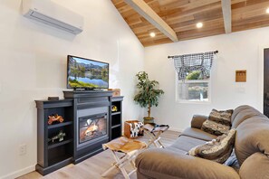 Ein Wohnzimmer mit Kamin, Fernseher und einer Couch.