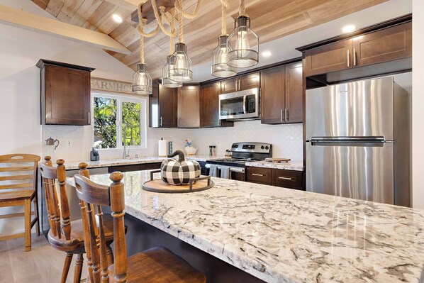 A kitchen with a marble countertop, stainless steel appliances, and wooden cabinetry. - Adorable 2-bedroom farmhouse in charming Placerville (Placerville)
