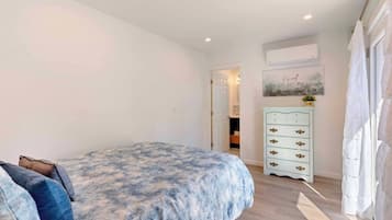 Une chambre à coucher comprenant un lit, une commode et une porte donnant sur une autre pièce.