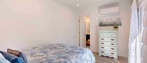 A bedroom with a bed, a dresser, and a door leading to another room.