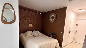 Un dormitorio con cama, espejo, ventilador de pared y puerta.
