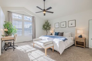 Ein Schlafzimmer mit Bett, Schreibtisch, Stuhl und Deckenventilator.