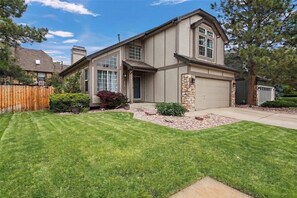 A two-story house with a garage, a well-maintained lawn, and a wooden fence. - Spacious 4BR Aurora Home with Sunroom and Fireplace (Aurora)