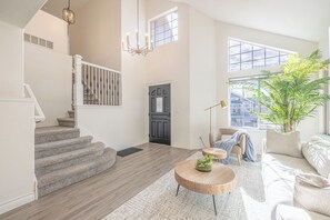 Ein geräumiges Wohnzimmer mit Treppe, großem Fenster und einer Topfpflanze.